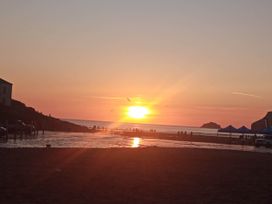 A beach scene at sunset with people and tents at Ground Floor Cornish Retreat Free Parking Bodmin