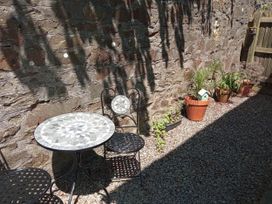 A garden with a table and chair near a stone wall at Ground Floor Cornish Retreat Free Parking in Bodmin