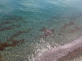 A clear view of the water with sand and rocks at the shore