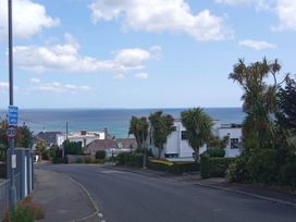 A view of houses and palm trees with the sea in the background at Ground Floor Cornish Retreat Free Parking in Bodmin