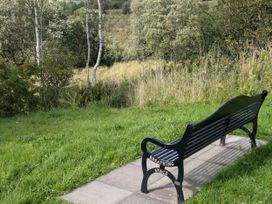 A bench in a grassy area surrounded by trees at Pet Friendly - Lodge at Riverview Holiday Park, Mangerton near Newcastleton