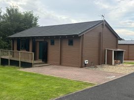 A lodge with a deck and storage shed at Pet Friendly - Lodge at Riverview Holiday Park, Mangerton near Newcastleton