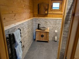 A bathroom with a sink and wooden cabinet at Pet Friendly - Lodge at Riverview Holiday Park Mangerton near Newcastleton