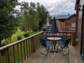 An outdoor area with a table and chairs at Pet Friendly - Lodge at Riverview Holiday Park Mangerton near Newcastleton