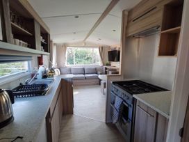 A kitchen with a cooking stove and a sofa area at 8Berth- SmartTV- CloseToBeach- FamilyFriendly in Mablethorpe
