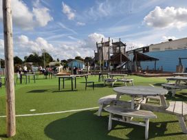 An outdoor play area with picnic tables and a climbing frame at 8Berth- SmartTV- CloseToBeach- FamilyFriendly in Mablethorpe