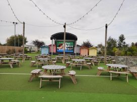 An outdoor area with picnic tables and a performance stage at 8Berth- SmartTV- CloseToBeach- FamilyFriendly in Mablethorpe