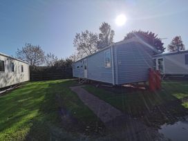 A static caravan with gas bottles and trees at 8Berth- SmartTV- CloseToBeach- FamilyFriendly in Mablethorpe