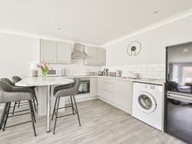 A kitchen with a washing machine and bar stools at 8Berth- SmartTV- CloseToBeach- FamilyFriendly in Millendreath near Looe