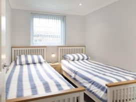A bedroom with two single beds and a window at 8Berth- SmartTV- CloseToBeach- FamilyFriendly in Millendreath near Looe