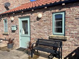 An outdoor entrance with a bench and plants at TBC