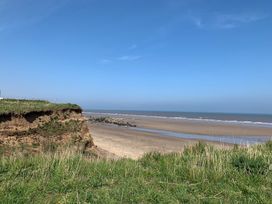 A view of a beach with a cliff and grass at TBC 