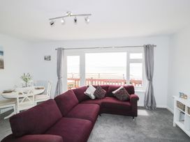 A living room with a sofa and dining area at The Cartwheel in Amroth