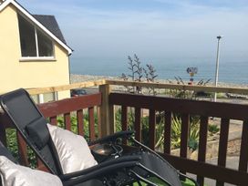 A deck with a chair and sea view at The Cartwheel in Amroth