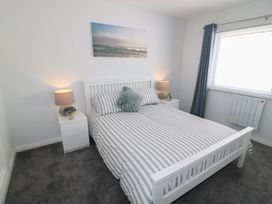 A bedroom with a bed and nightstand at The Cartwheel in Amroth