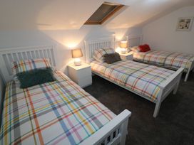 A bedroom with three beds and a lamp on a nightstand at The Cartwheel in Amroth