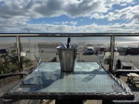 A balcony with a champagne bucket and glasses overlooking the beach at The Cartwheel in Amroth