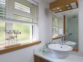 A bathroom with a sink, mirror, and shower at 6 Knowle Court in Salcombe