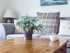 A living room with a couch, table, and potted plant at 6 Knowle Court Salcombe
