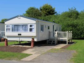 A mobile home with a deck and steps at 84 Sandhills in Ingoldmells