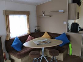 A dining area with a round table and blue and yellow cushions at 84 Sandhills in Ingoldmells