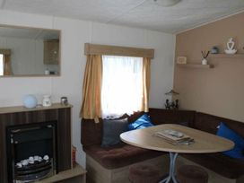 A living room with a table and seating area at 84 Sandhills in Ingoldmells