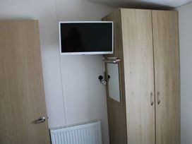 A bedroom with a television and wardrobe at 84 Sandhills in Ingoldmells