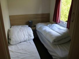 A bedroom with two beds and a lamp at 84 Sandhills in Ingoldmells