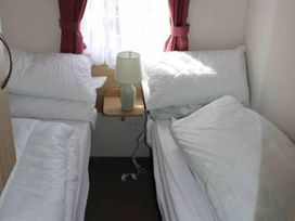 A bedroom with two beds and a lamp at 84 Sandhills in Ingoldmells