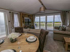 A living room with a dining area and sofa at The Dorchester at Bay View in New Quay