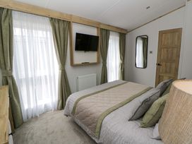 A bedroom with a bed, television, and curtains at The Dorchester at Bay View, New Quay