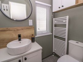 A bathroom with a sink, mirror, toilet, and radiator at The Dorchester at Bay View in New Quay