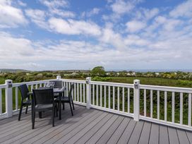 A deck with a table and chairs overlooking a view at The Dorchester at Bay View New Quay