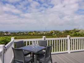 An outdoor seating area with a table and chairs overlooking the sea at The Dorchester at Bay View in New Quay