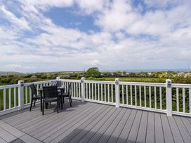 A deck with table and chairs overlooking a landscape at The Dorchester at Bay View New Quay