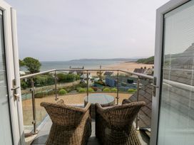 A balcony with wicker chairs and a table overlooking the sea at Hillside