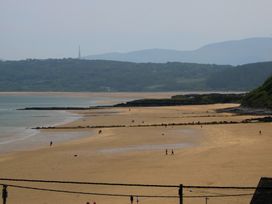 A beach with people walking and hills in the background at Hillside