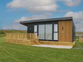 A house with a deck and large windows at Heron in Haverigg