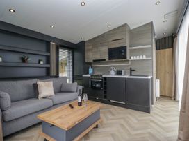 A living room with a sofa and kitchen area at Heron in Haverigg