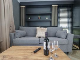 A living room with a sofa, table, wine bottle, and glasses at Heron in Haverigg