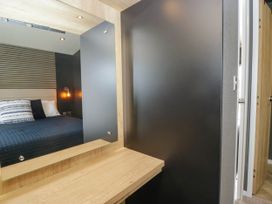 A bedroom with a bed and a mirror at Heron in Haverigg
