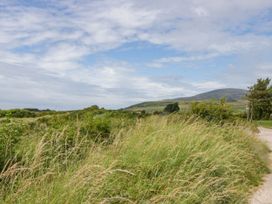 A view of grass and a path with mountains in the background at Heron in Haverigg