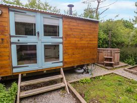 A wooden hut with steps and a hot tub in the outdoor area at Shepherds Hut, Truro