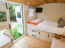 A bedroom with a bed and open door at Shepherds Hut in Truro