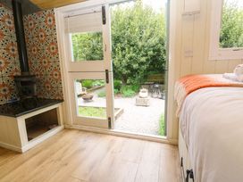 A bedroom with a wood stove and glass door opening to a garden at Shepherds Hut in Truro