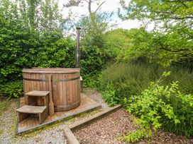 A hot tub with wooden steps and plants at Shepherds Hut in Truro