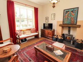 A living room with a sofa, tv, and fireplace at The School House in Penrith