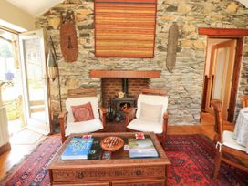 A living room with a fireplace and wooden chairs at The School House in Penrith