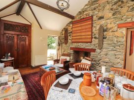 A dining room with a stone wall and wooden furniture at The School House in Penrith