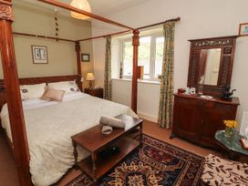 A bedroom with a four-poster bed and a wooden table at The School House in Penrith